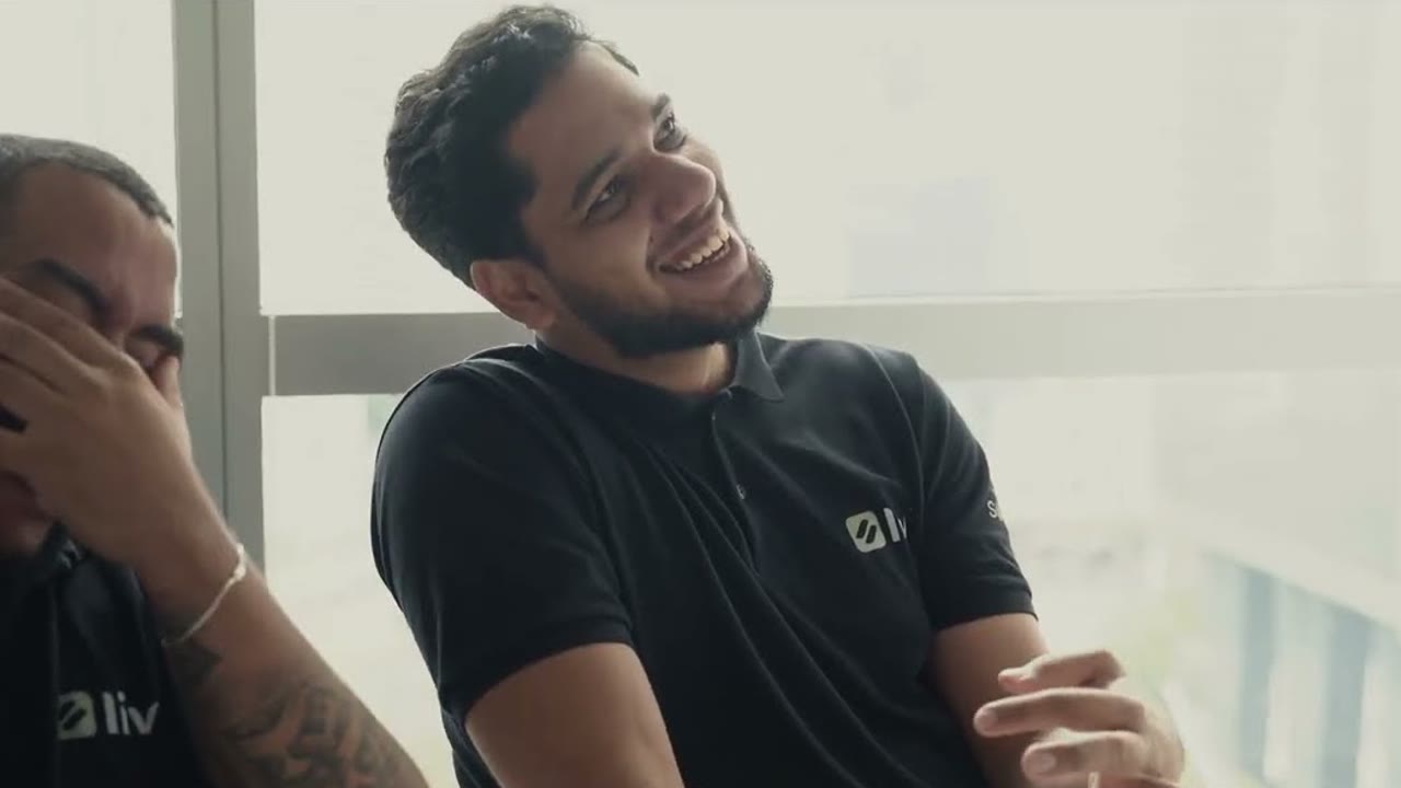 Dois integrantes da equipe da LIV Energia Solar riem durante a visita ao escritório da Solfácil, em São Paulo.